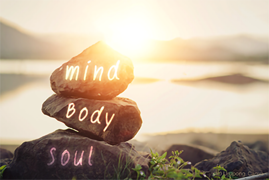 Body, mind, soul auf Steinen geschrieben. Sonnenuntergang und See im Hintergrund.