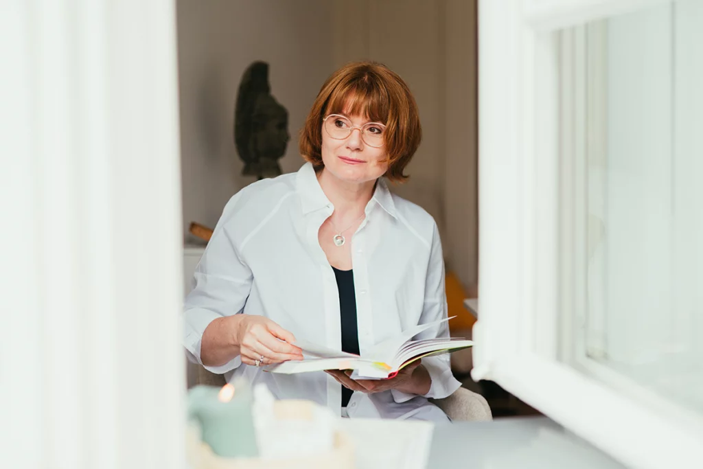 Frau mit Buch, schaut aus dem Fenster