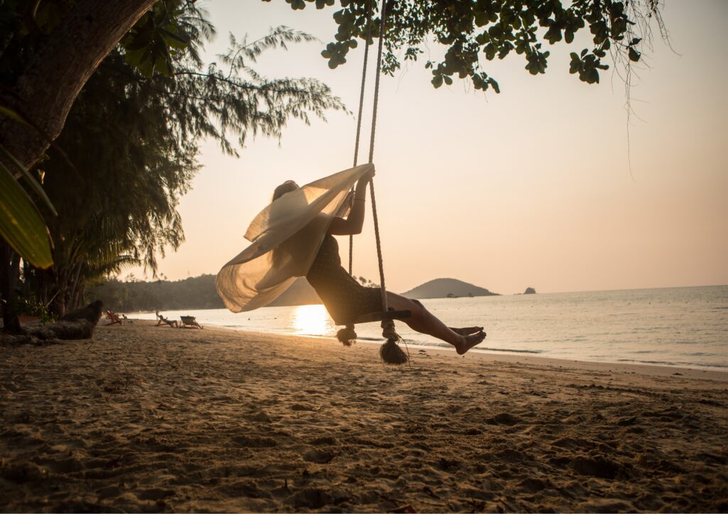 Frau 50plus auf einer Reise, am Strand in einer Schaukel